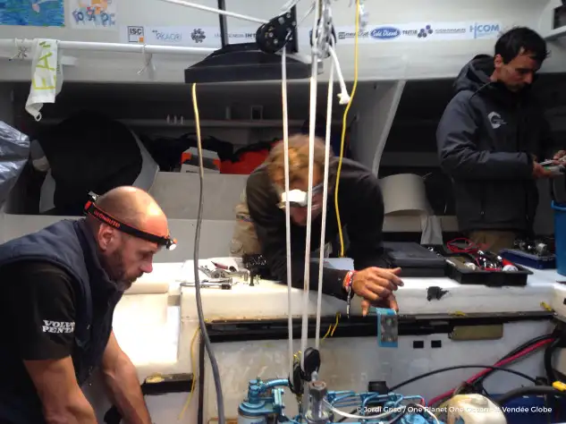 Didac Costa (derecha) en el interior del barco con Aleix Gelabert y un técnico acabando de retocar el motor.