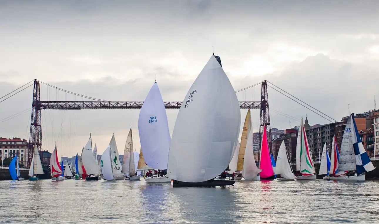 ‘Ashandar WOP’ y ‘Boreal’ ganan con poco viento la clásica Regata del Gallo - Esta tradicional prueba, que tuvo 80 barcos participantes, cerró el calendario de 2016 del Real Club Marítimo del Abra-Real Sporting Club - El paso del espectacular grupo de embarcaciones bajo el Puente Colgante supuso de nuevo una imagen única